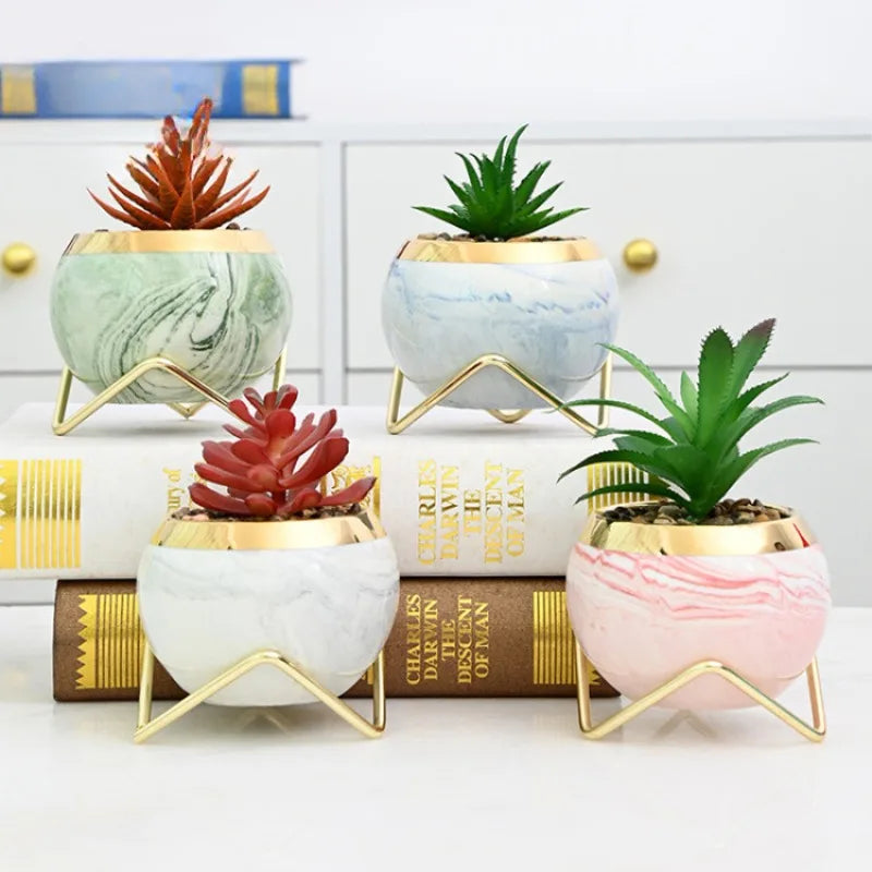 Pastel pink marble flower pots with gold iron stands on desk
