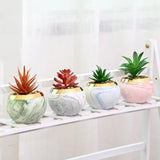 Set of marble ceramic flower pots with iron stands on table
